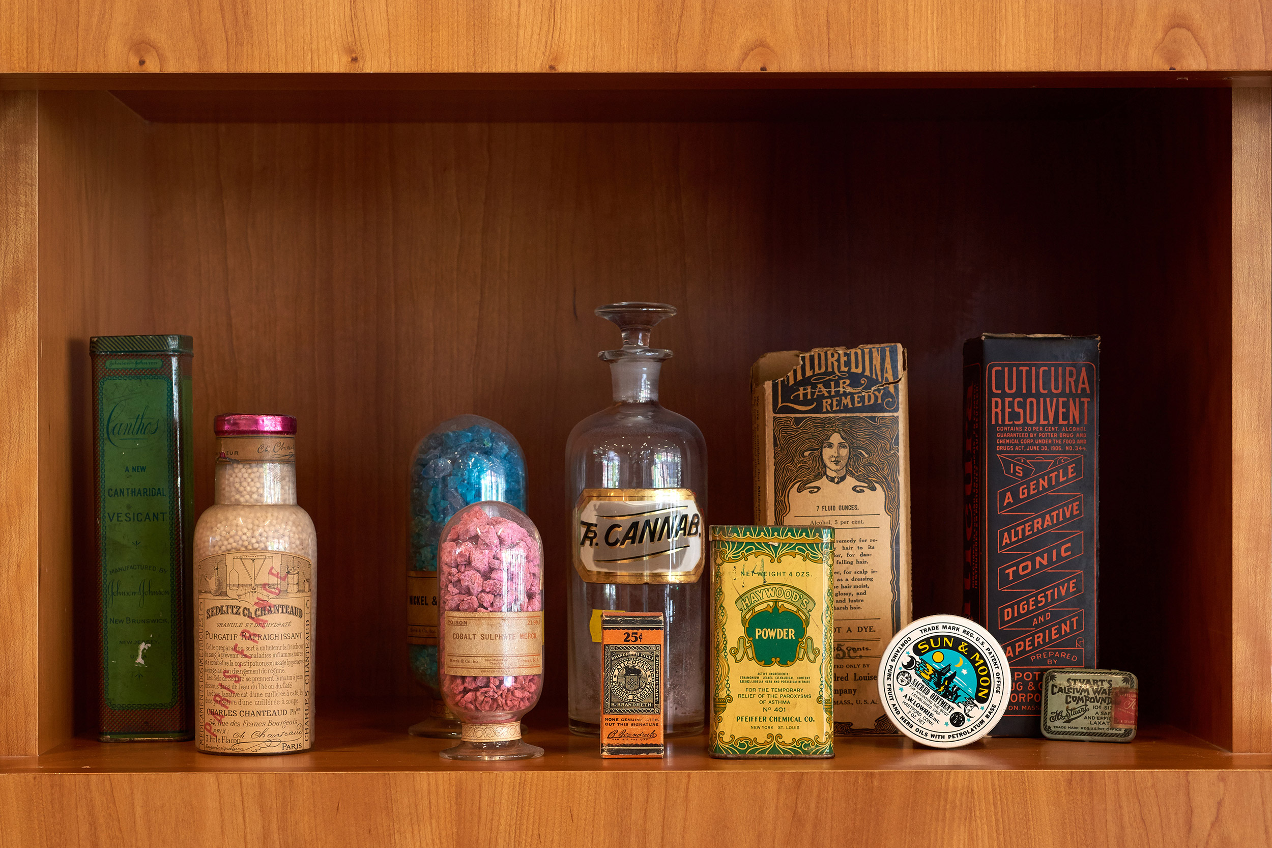 tintures and bottles sit inside a wooden cabinet