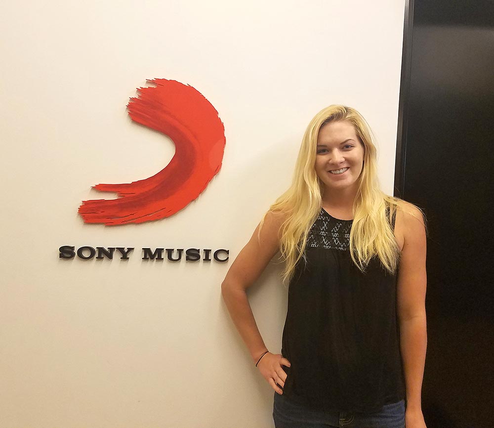 Maggie Quackenbush in front of Sony Music logo on wall
