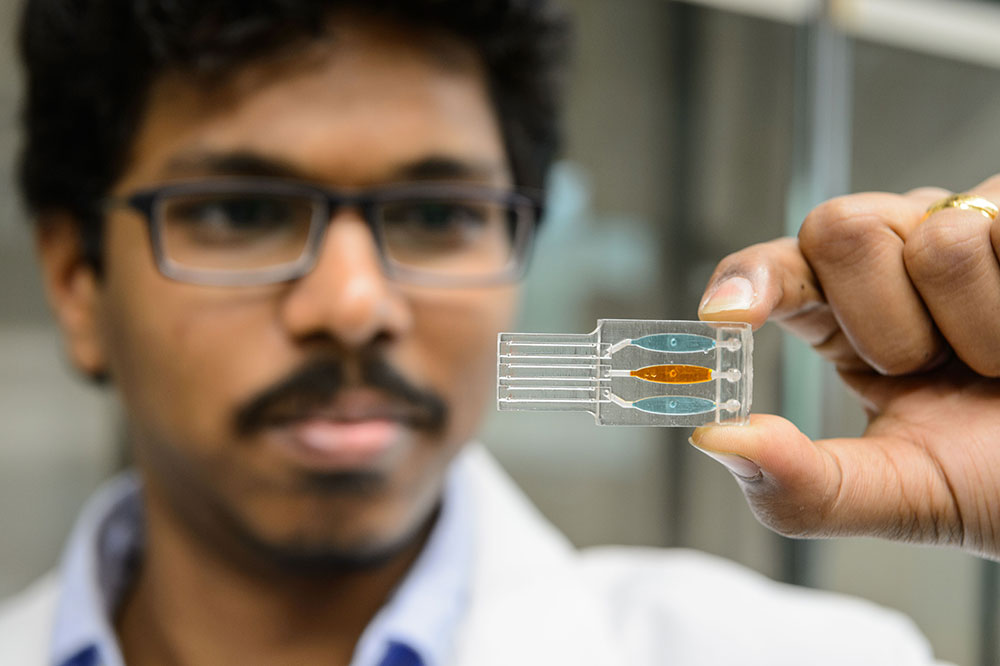 Postdoctoral researcher Karteek Kadimisetty holds the 3-D printed sample chamber of his genetic toxicity testing device. (Peter Morenus/UConn Photo)