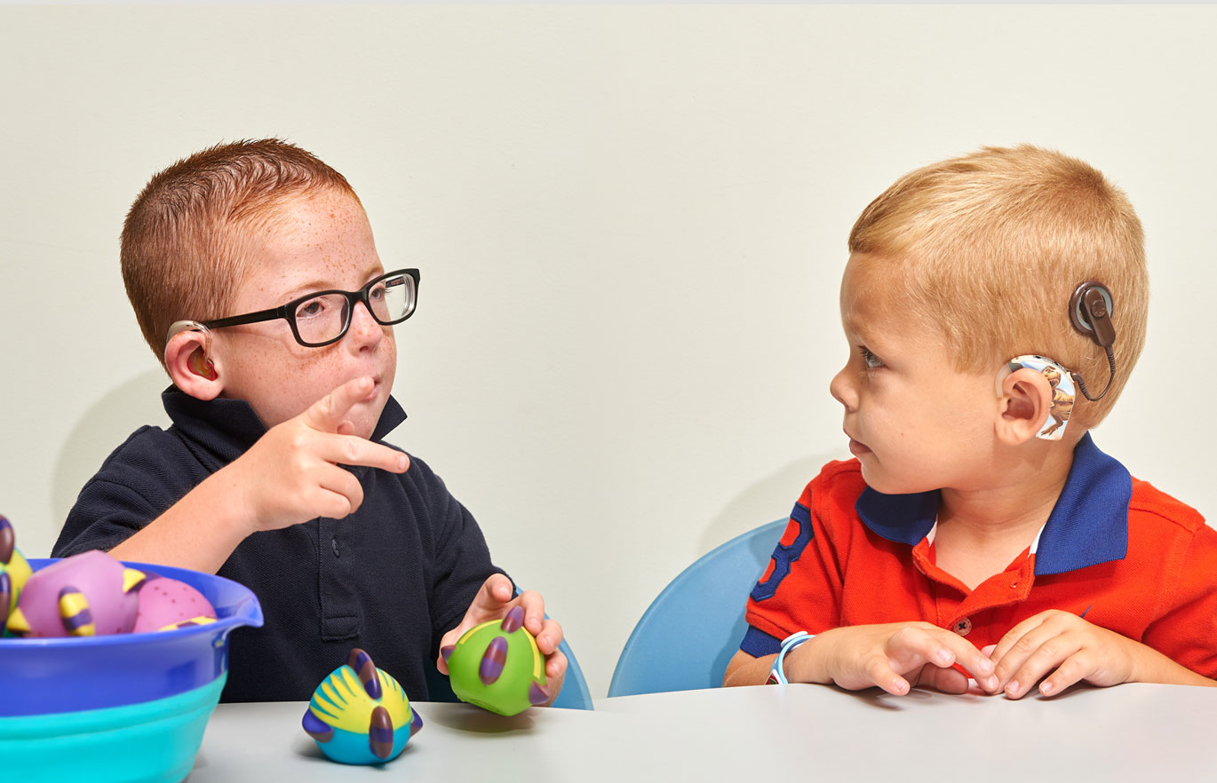 Two children looking at each other doing sign language