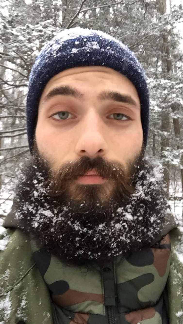 heavily bearded male in snow covered parka