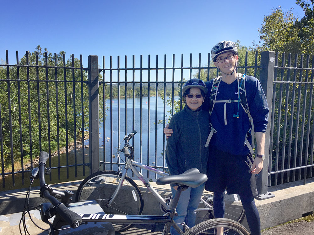Then pharmacy graduate student Celeste Cheung ’18 Pharm.D. (right) during a 20-mile bike ride along the Farmington River last year with her patient, friend, and “Cambodian mom” Lila Plawecki.