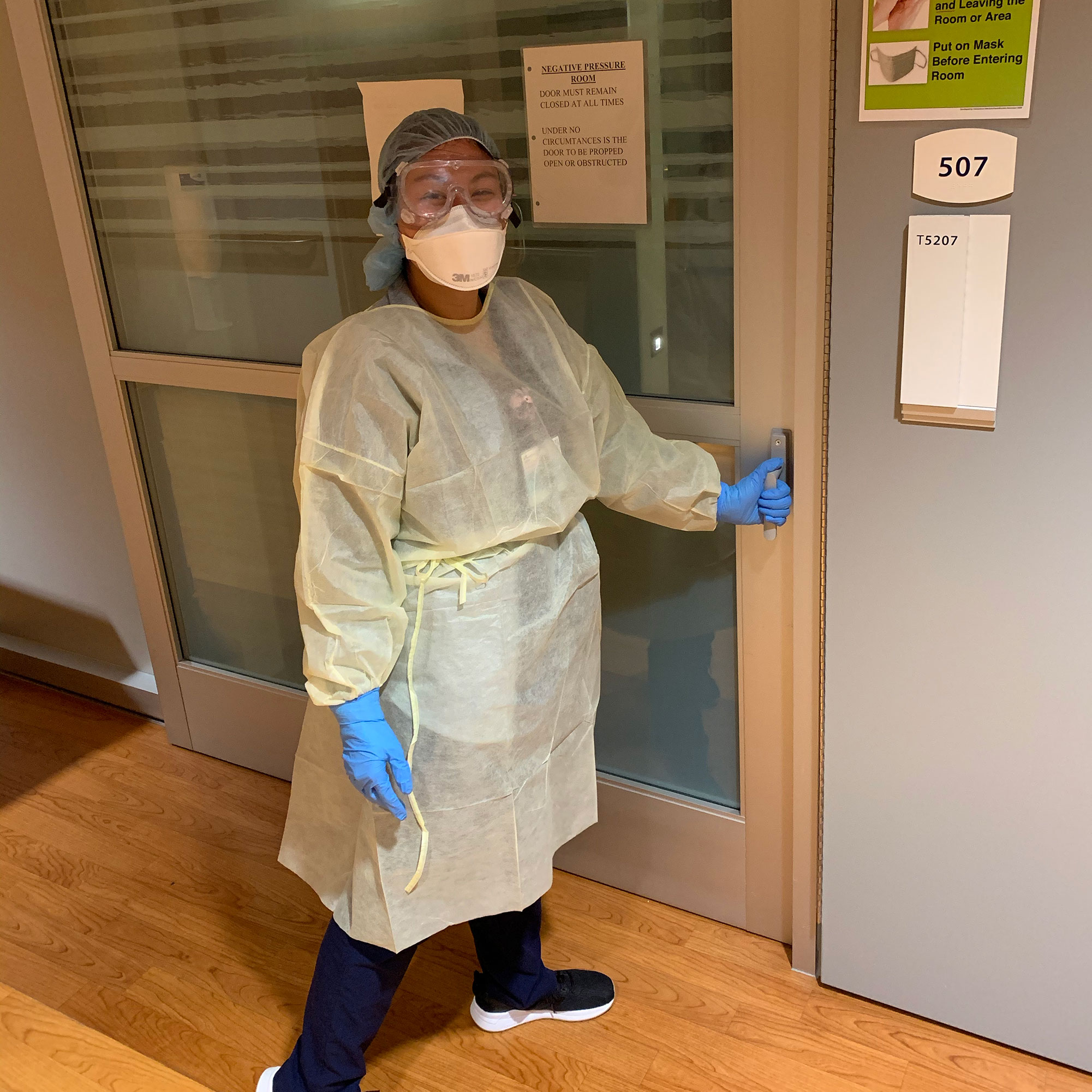 nurse stands in front of door with full ppe on