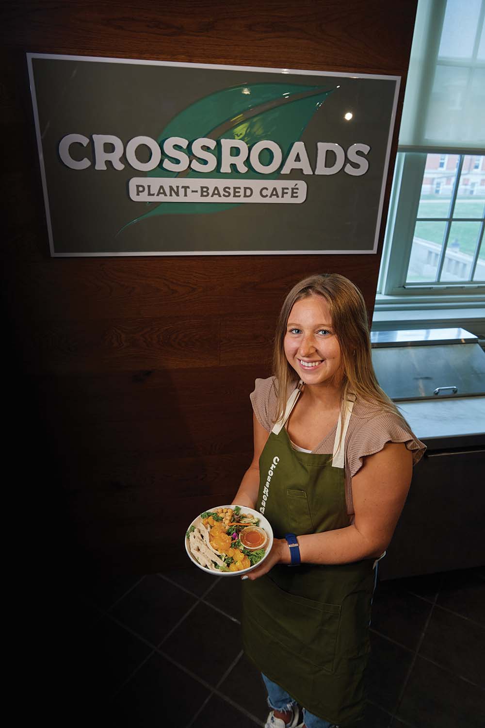 Maddie Pickett showcases the orange chopped salad in front of the Crossroads Cafe sign