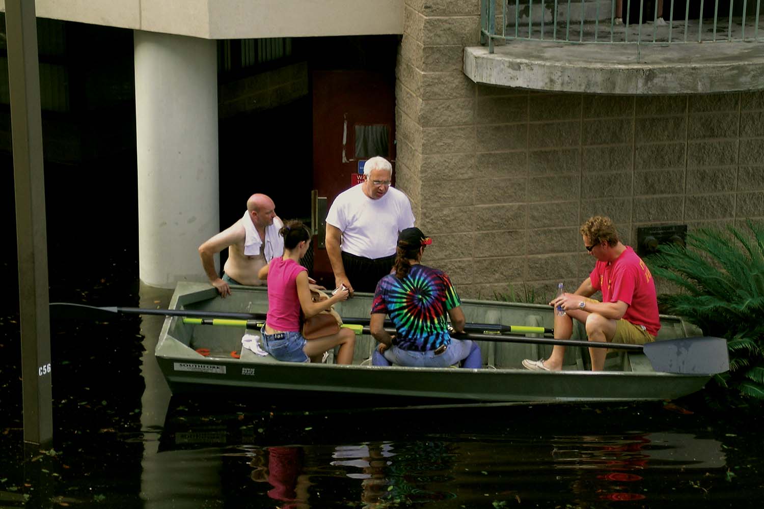 cowen on small boat directing student volunteers in the middle of a large flood