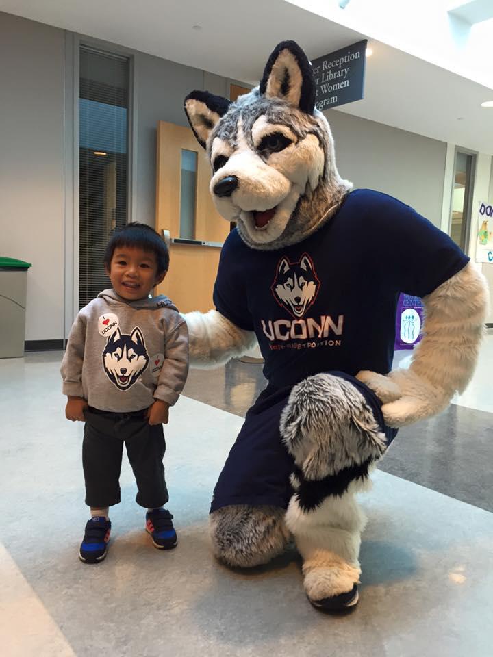 Allison and Xuan's son poses with jonathan, UConn'smascot