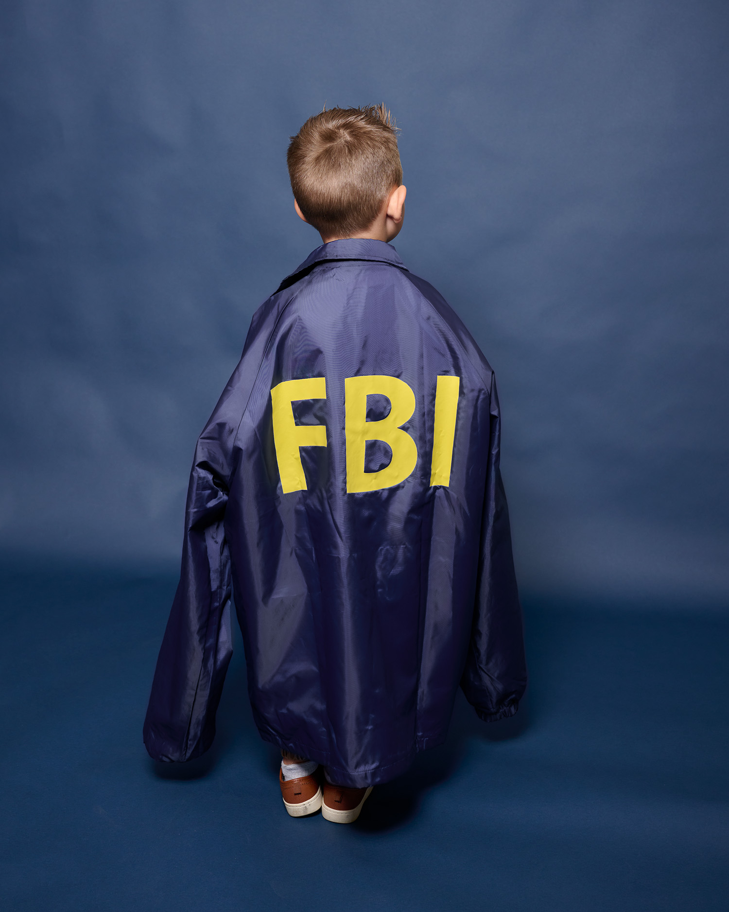 kid wears cape with bright yellow letters, FBI