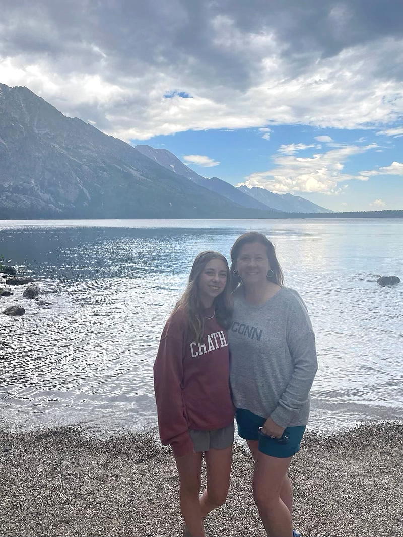 Two smiling women in front of a lake