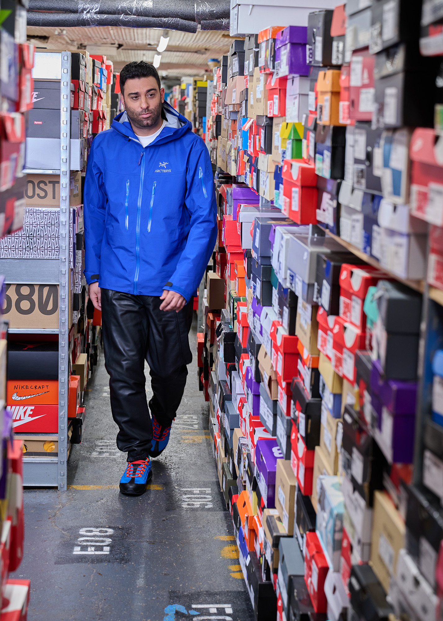 Joe La Puma walks past shelves of limited edition and rare sneakers from popular sneak brands.