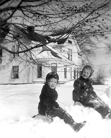 archival photo of a young Janet McMillan Rives and sister playing in the snow outside the house, taken around 1949