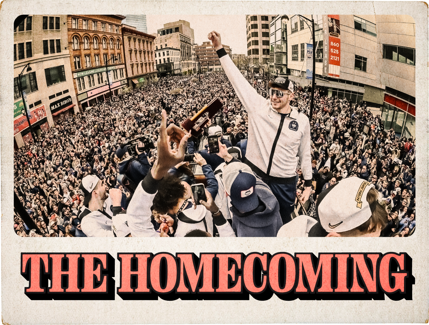 Vintage-style trading card with the words “The Homecoming” on the bottom and an image of a crowd of people filling the streets of downtown Hartford behind a group of UConn men’s basketball players holding up their arms and a trophy while standing on top of a double-decker bus during their 2024 victory parade.