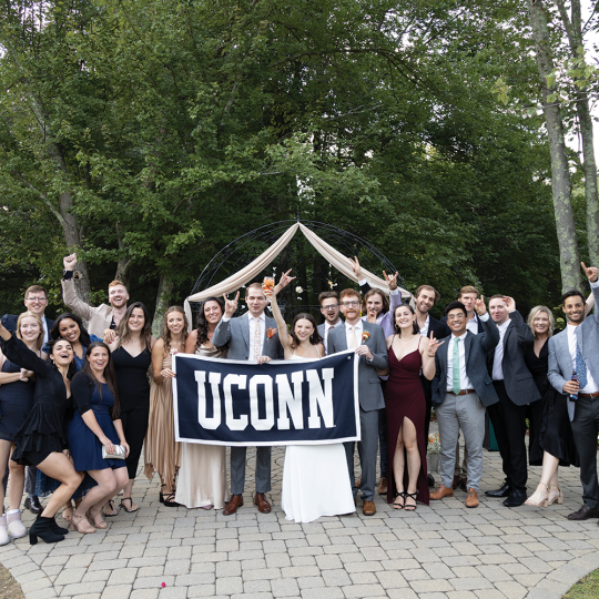 Case and Kaplan wedding party pose and hold a UConn banner