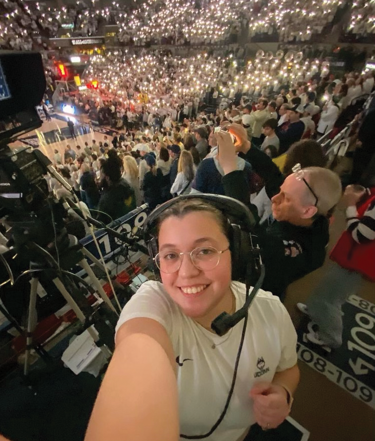 Sydney works working Camera 2 at a crowded Gampel Pavilion during a live basketball game.