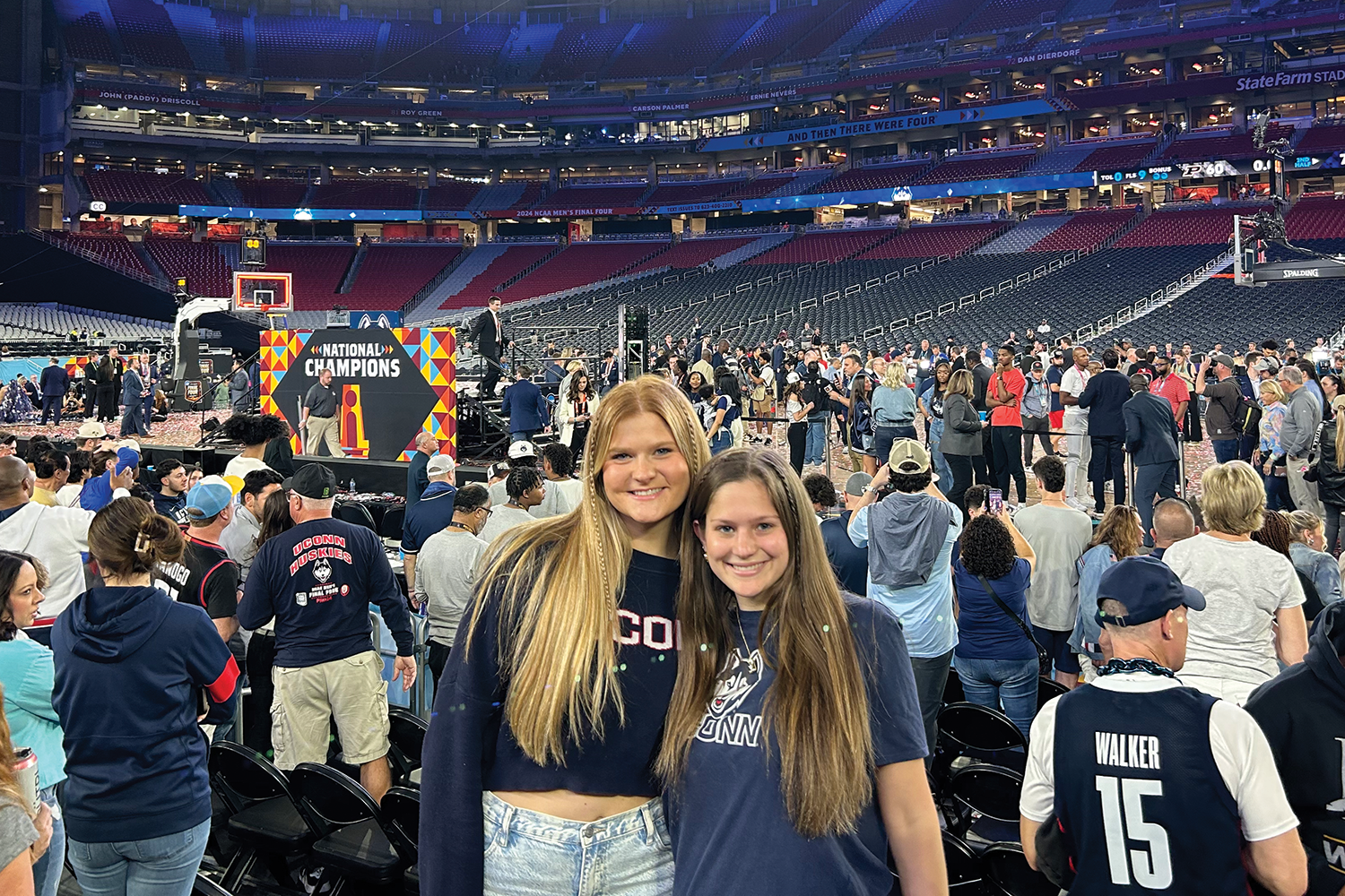 Julia and twin sister pose behind crowd of others waiting for the start of Final Four basketball game in Phoenix