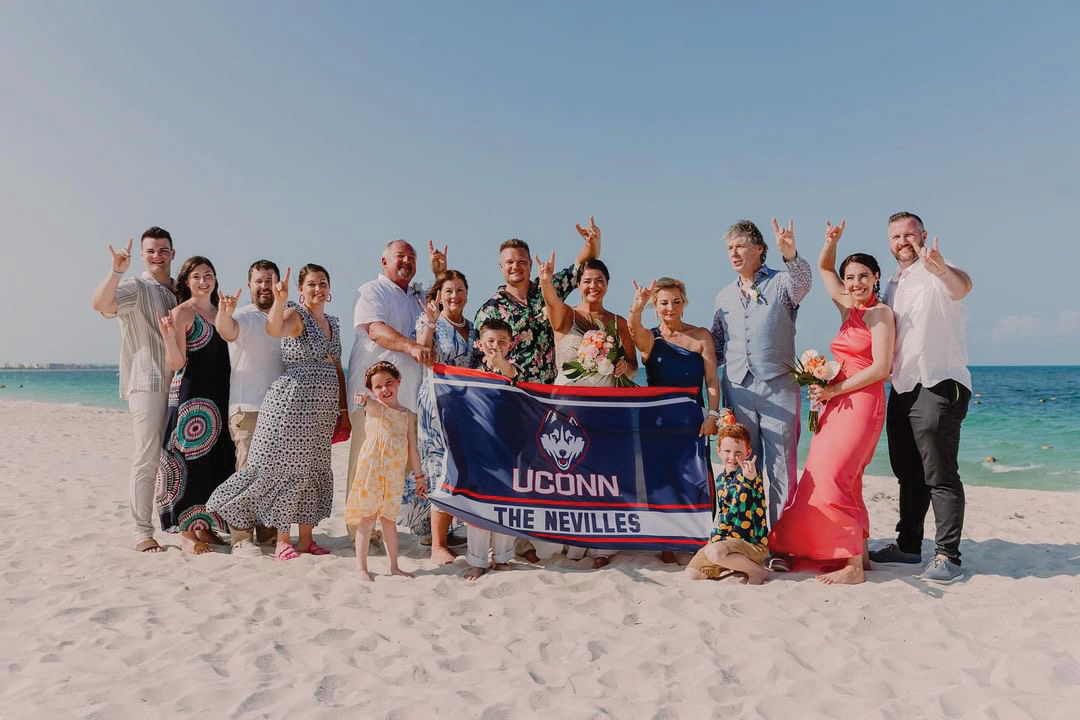 Kaszuba-Neville wedding party celebrate on a beach with hands up and smiles