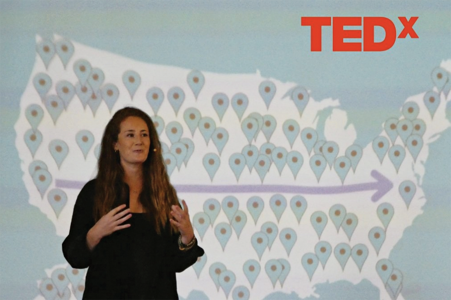 Michelle Wax stands in front of large screen while giving TedX talk