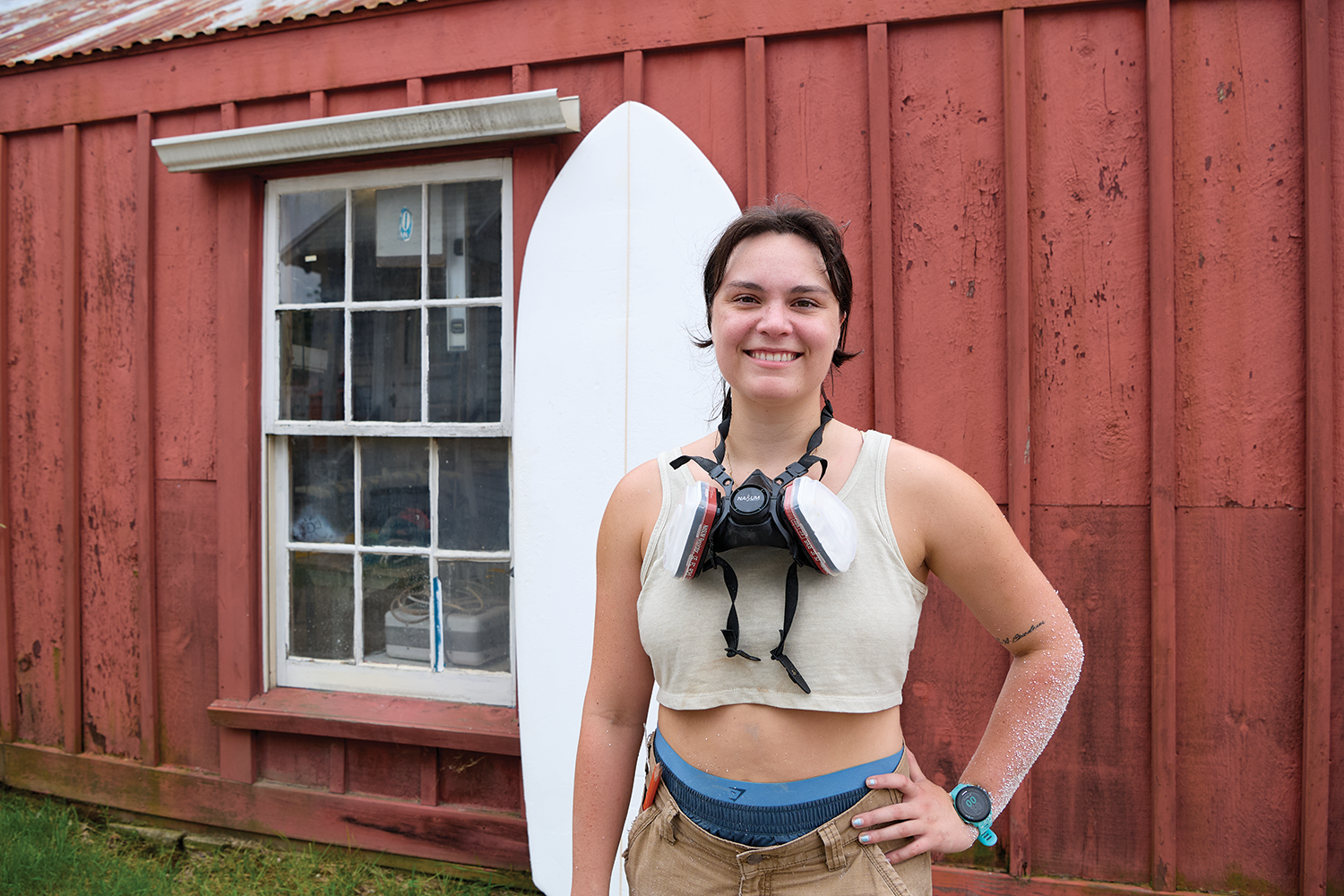 Amelia Martin poses at Mystic Seaport Museum workshop that she uses to shape surfboards