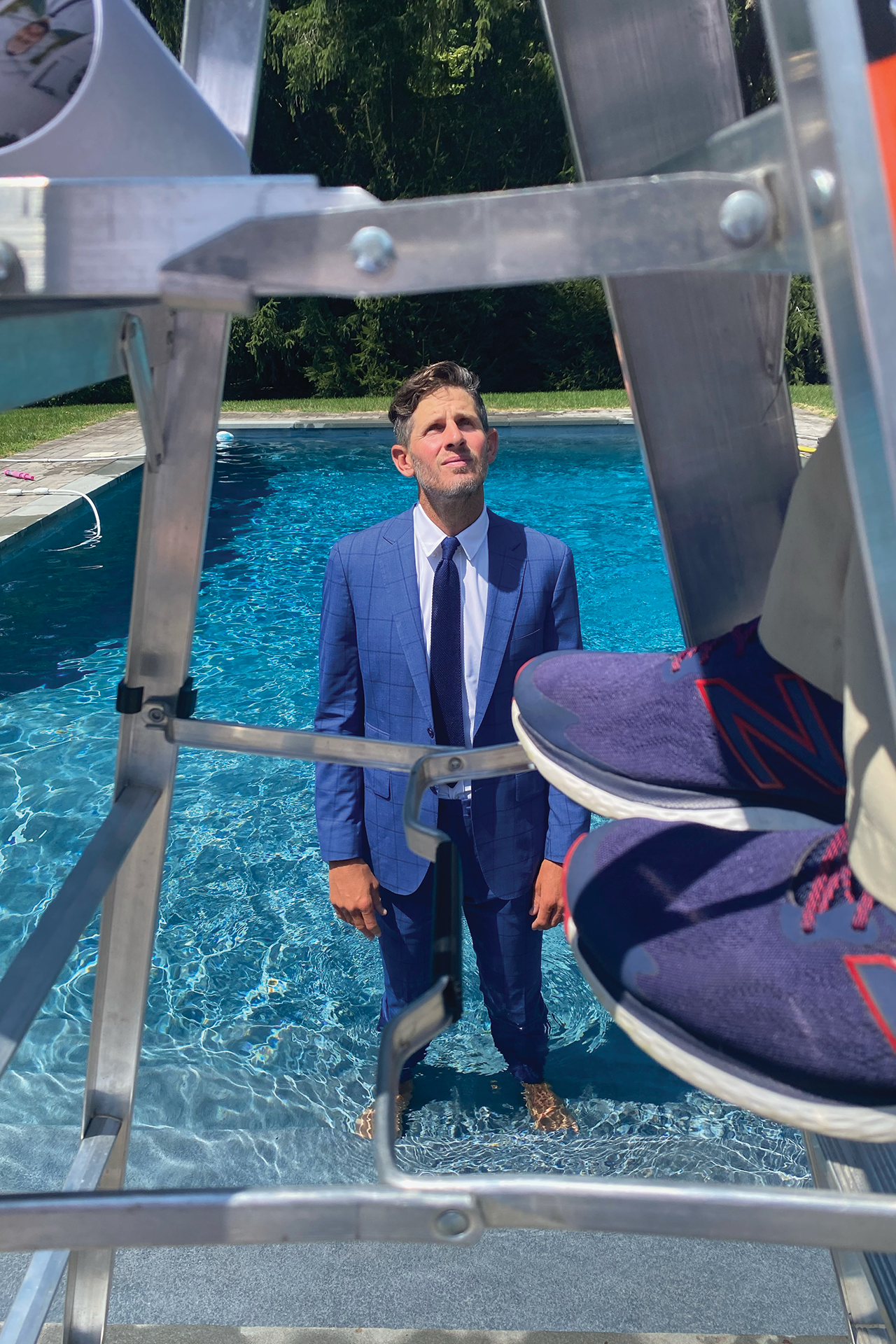 Dan Orlovsky looks up while wading in the shallow end of his home pool while photographer stands on a small ladder