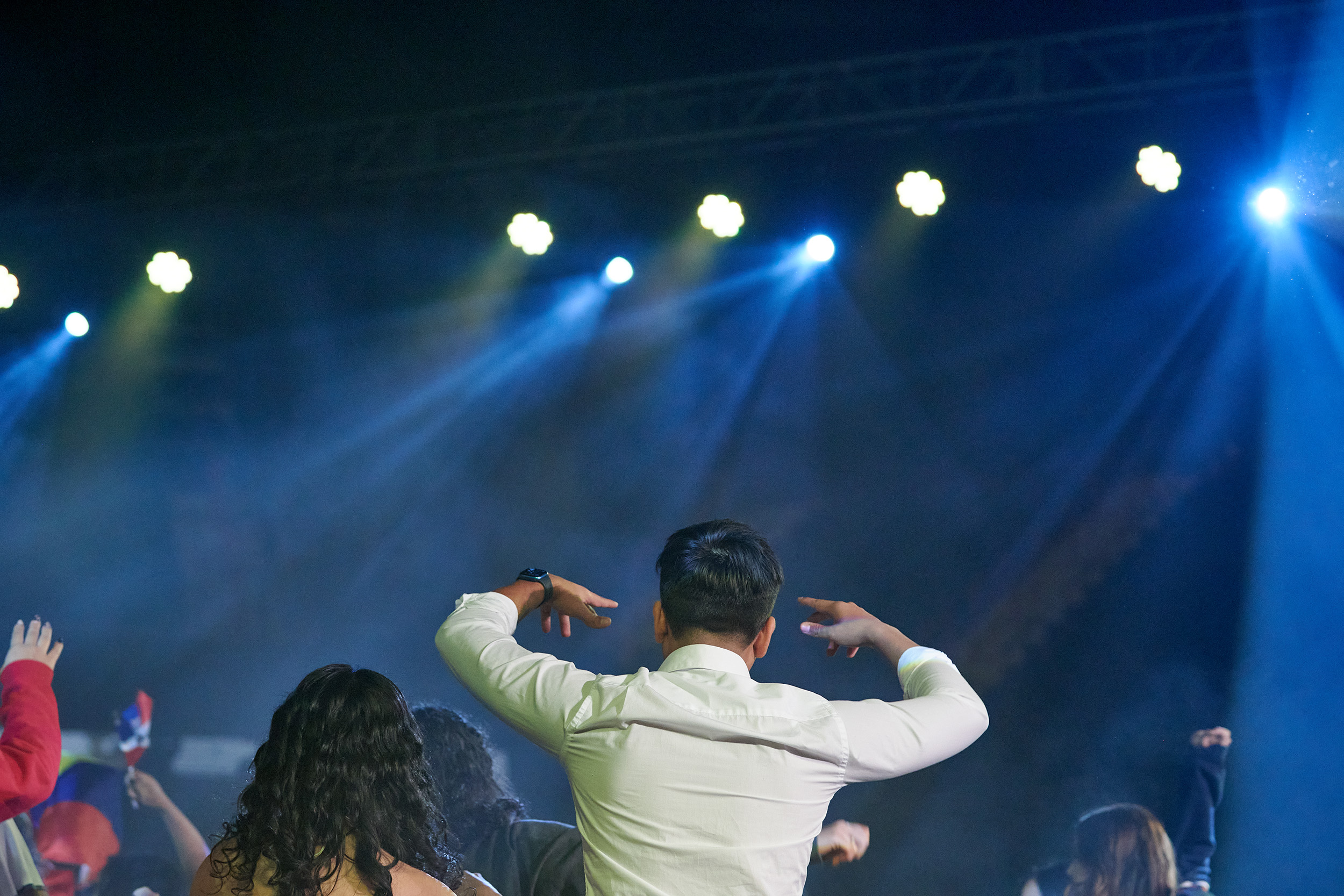 Male student stands and puts his hands up, cheering for a performance from the audience.