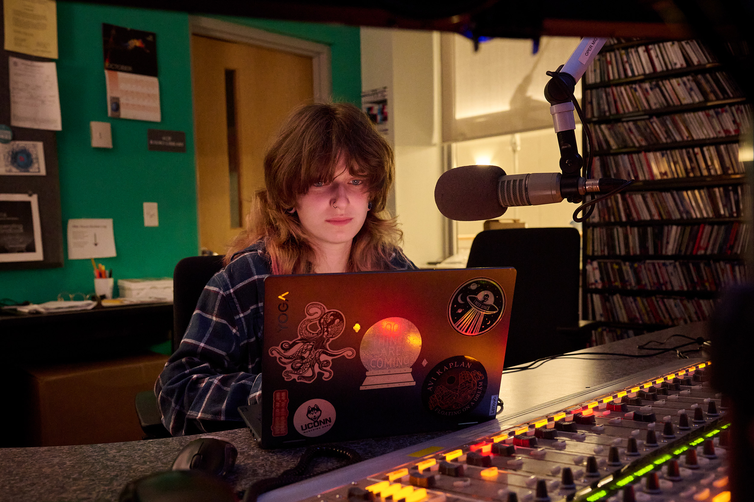 student looks at her laptop, with radio equipment and a microphone in front of her.