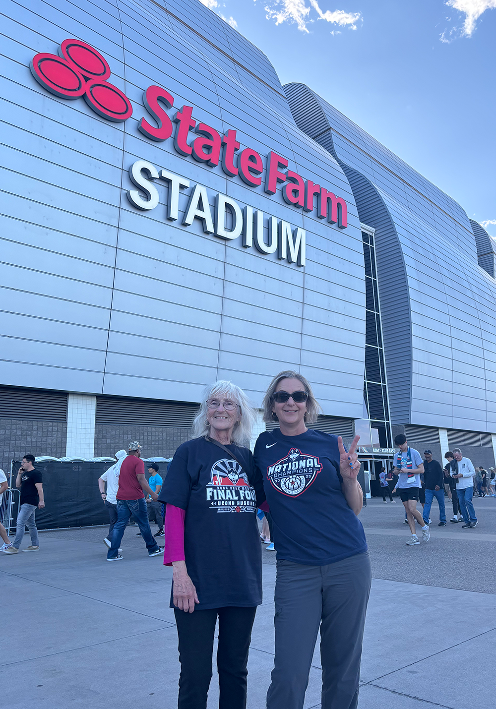 Vanessa and her mother pose with peace sign hand gesures at UConn basketball game in front of State Farm Stadium