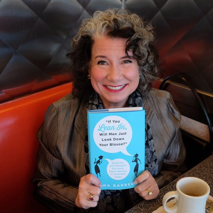 Gina holds a copy of her latest book, If You Lean In, Will Men Just Look Down Your Blouse?