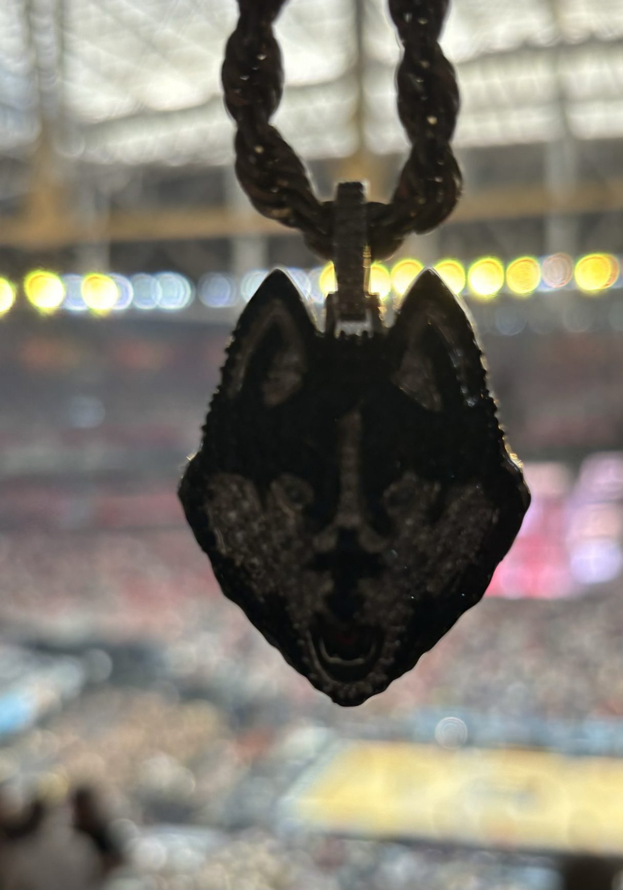 UConn husky bling hangs on a chain in front of a game in full swing at the Gampel Pavillion