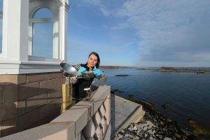 Penny Vlahos replaces a seasonal cartridge on an air sampling device attached to the Avery Point Lighthouse