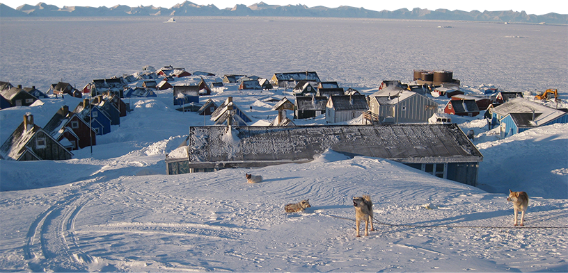 a snow covered research station in Greenland. It's surrounded by vast tundra. Huskies howl in the foreground