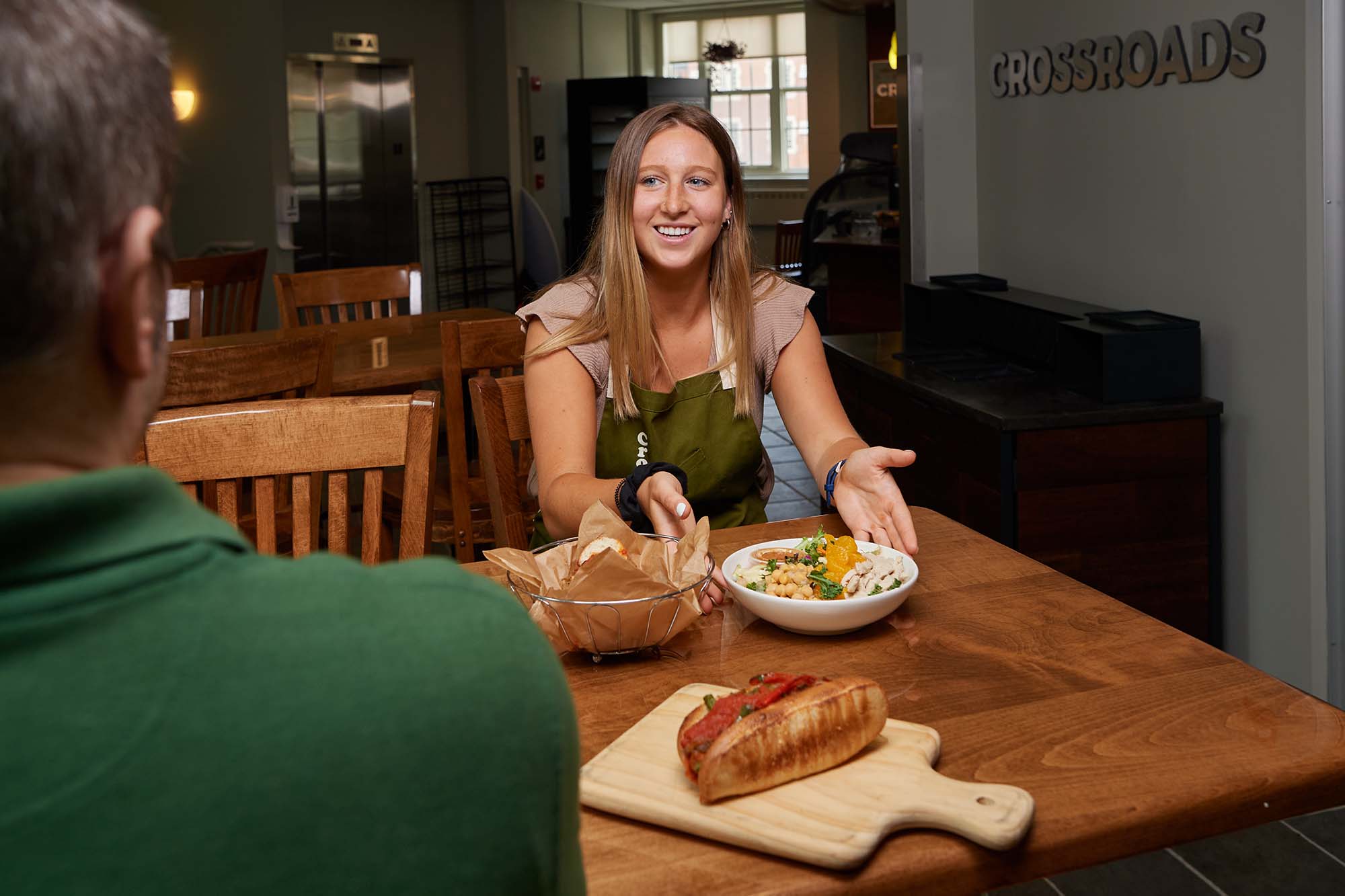 Maddie Pickett gestures to orange faux chicken salad on the table at Crossroads Cafe