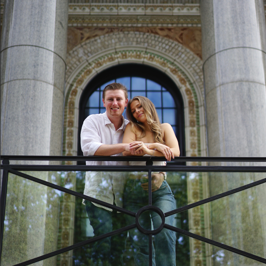 Will Butler and Rebecca Ouellette stand holding each other in front of Hartford Times building on UConn’s Hartford Campus