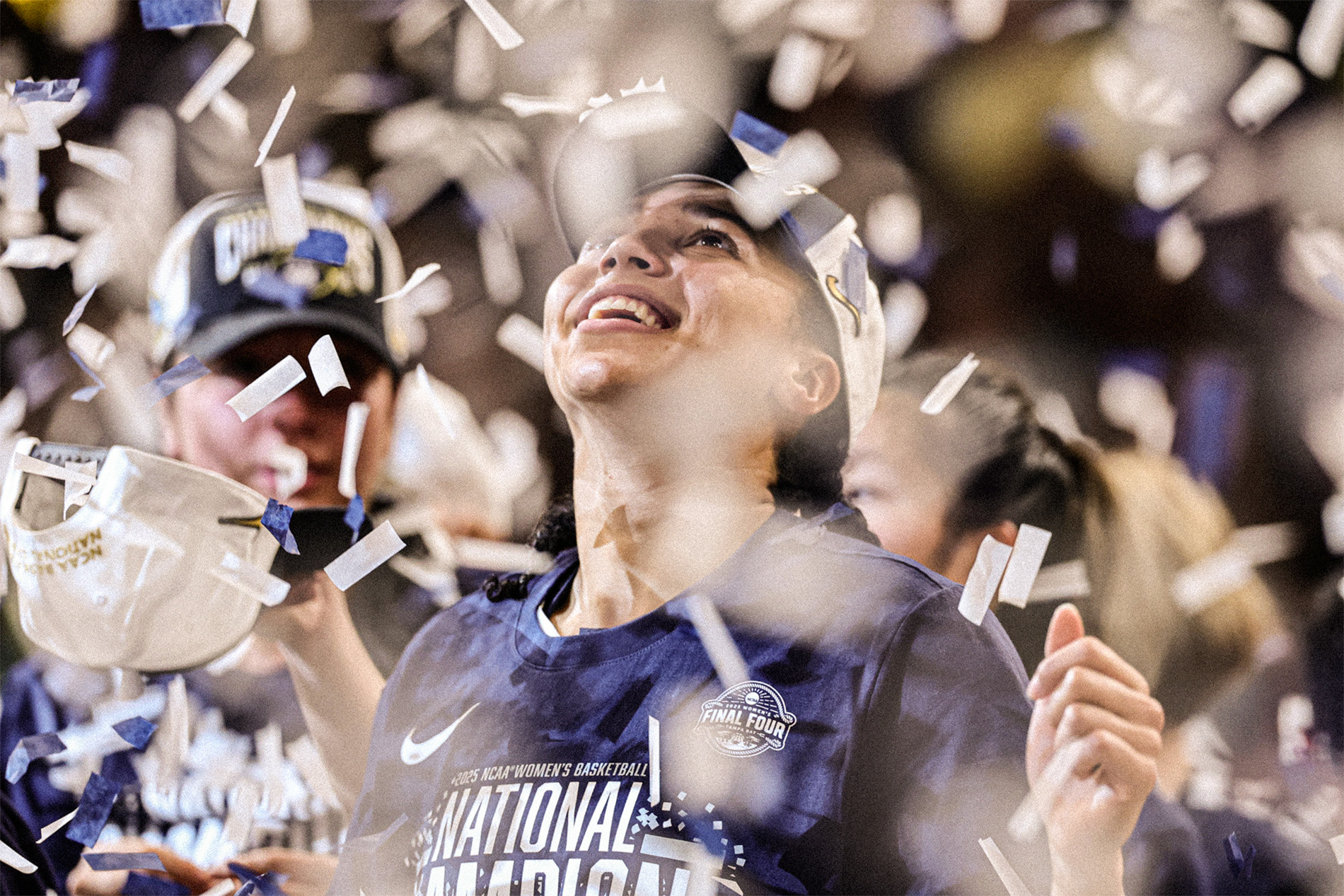 GettyImages-2208882363-sized Azzi Fudd wears a commemorative national championship hat and t-shirt while she smiles and looks up as confetti falls around her during the victory celebrations.