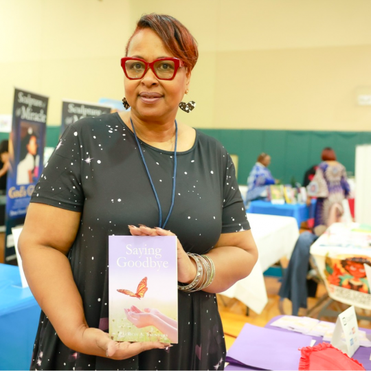 Patricia A. Saunders holding up book