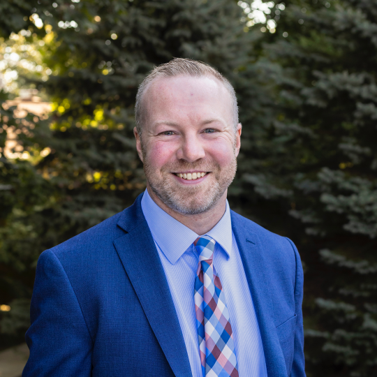 James Geisler in blue suit, blue shirt and patterned tie.