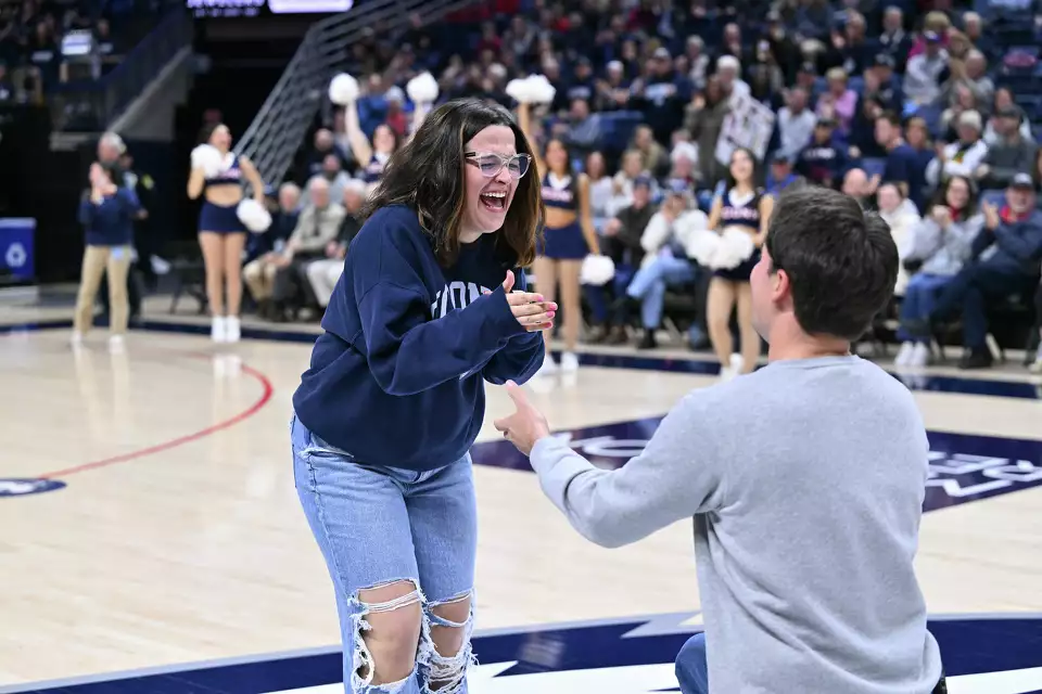 Proposal Woman being proposed to on the court at Gampel Pavillion during UConn Women’s Basketball game. Boyfriend down on one knee in full stadium.
