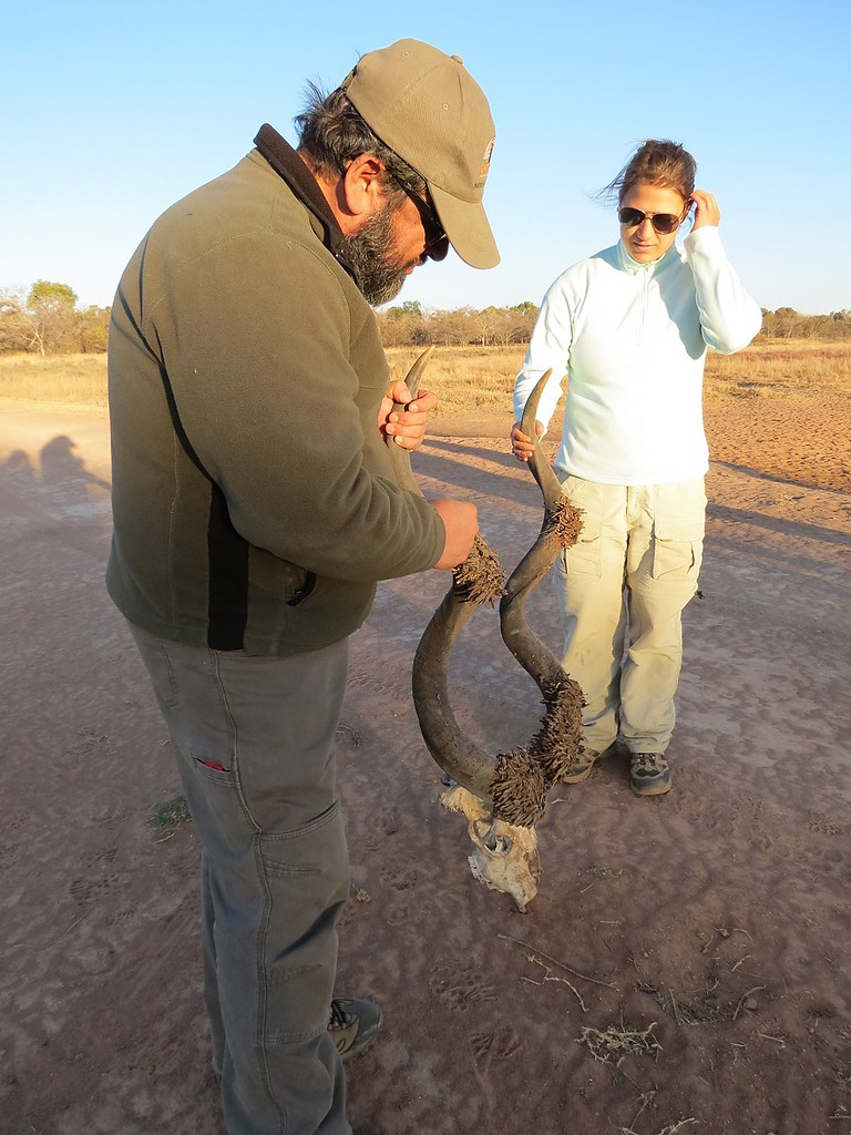 Morty Ortega and Samantha Kremidas each hold a large, coiled antler attached to an animal skull