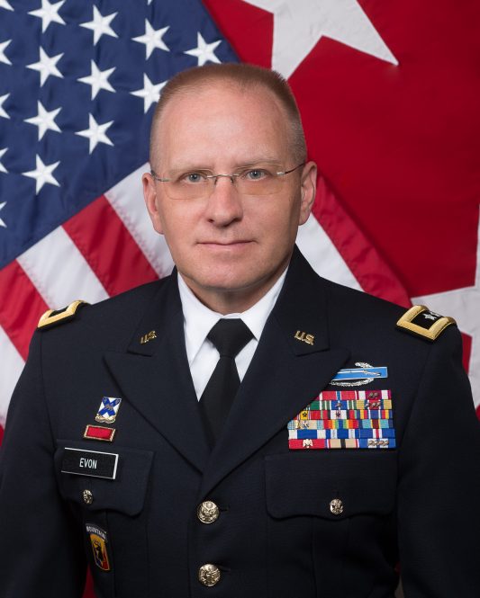 Major General Francis Evon in regalia posing in front of an American flag