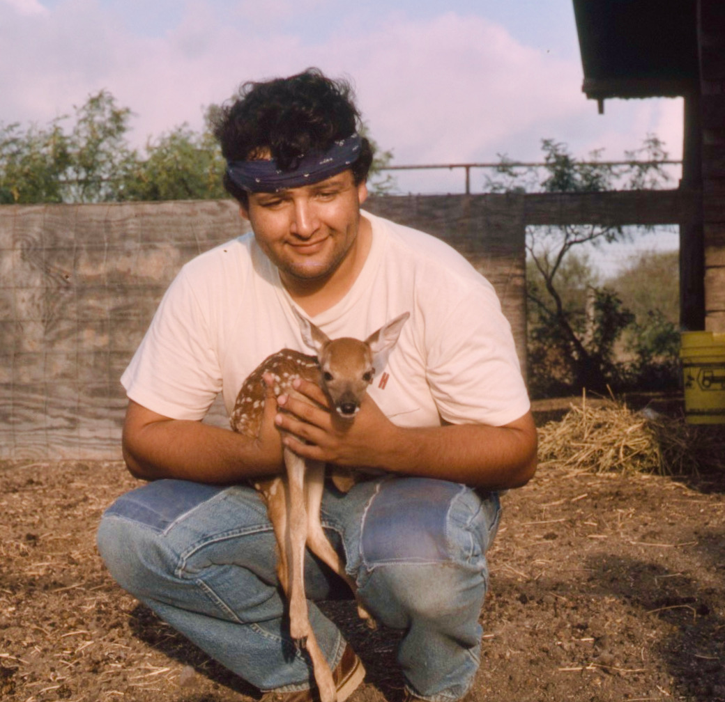 Morty Ortega wearing a white T-shirt and jeans holds a fawn, facing the camera, in a 1987 photo