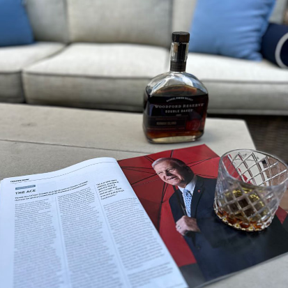 An issue of UConn Magazine opened to a picture and story on Andy Bessette with a glass of brown liquid and a bottle of Woodford Reserve on a coffee table