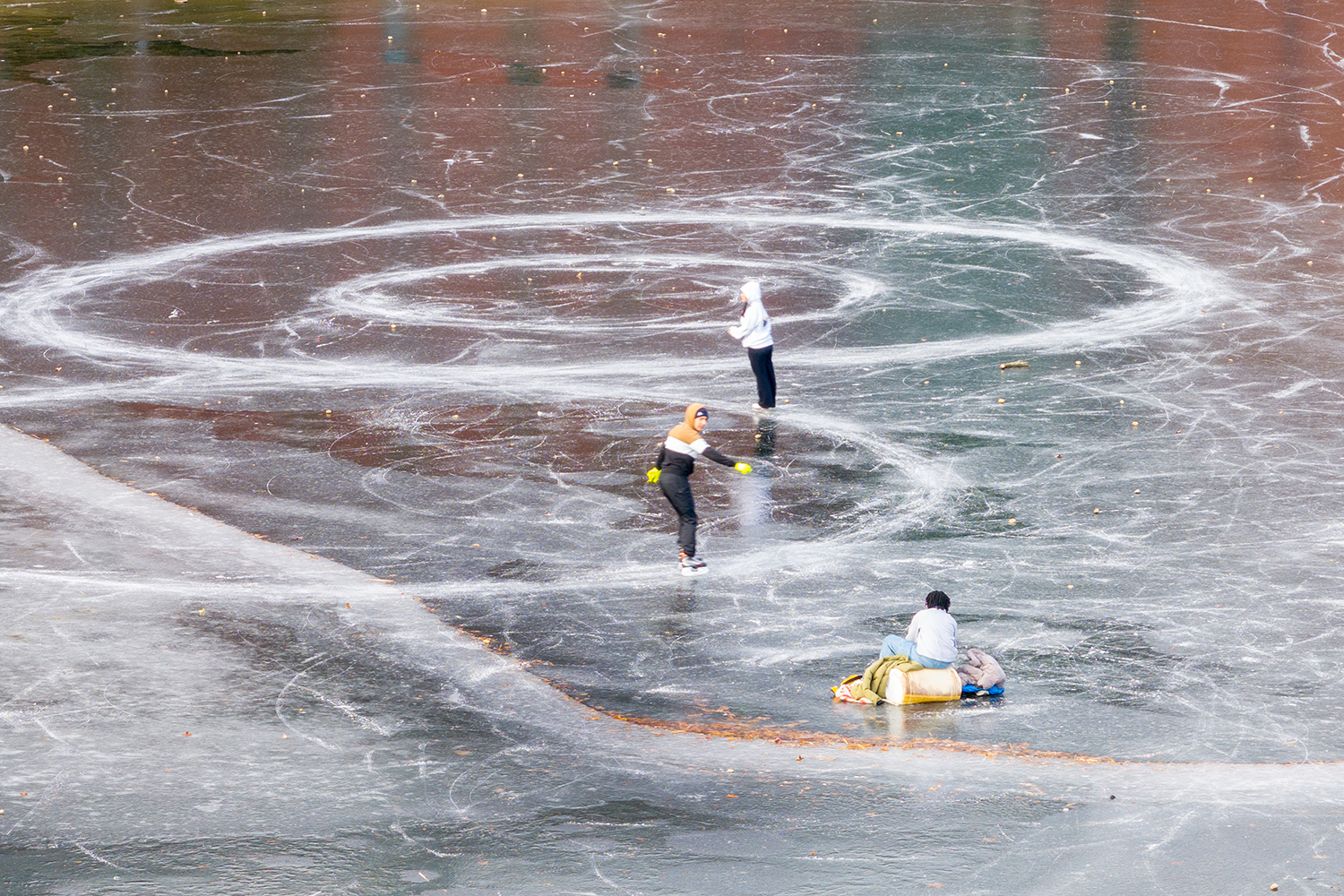 Students ice skating on a frozen over Swan Lake.