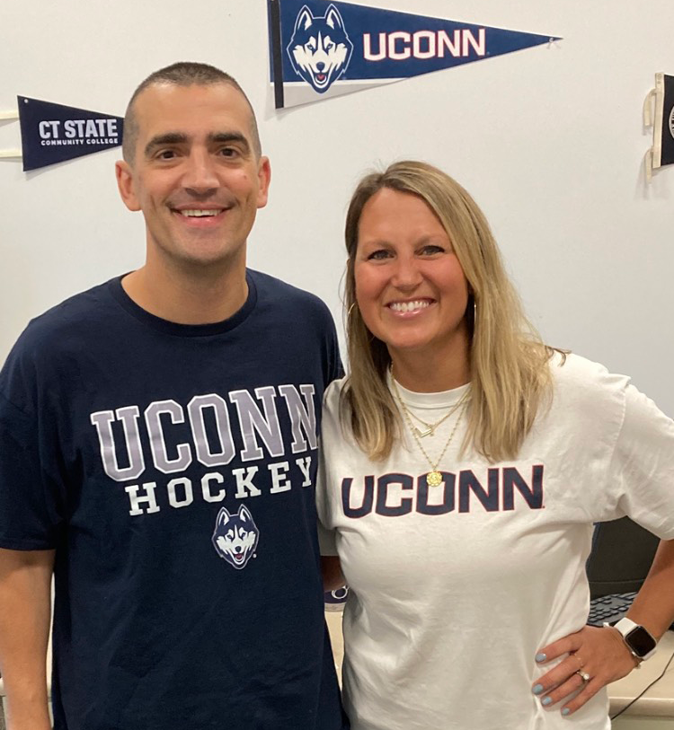 Kristi (Tokarz) Maler and Adam Coppola pose together in front of UConn paraphernalia