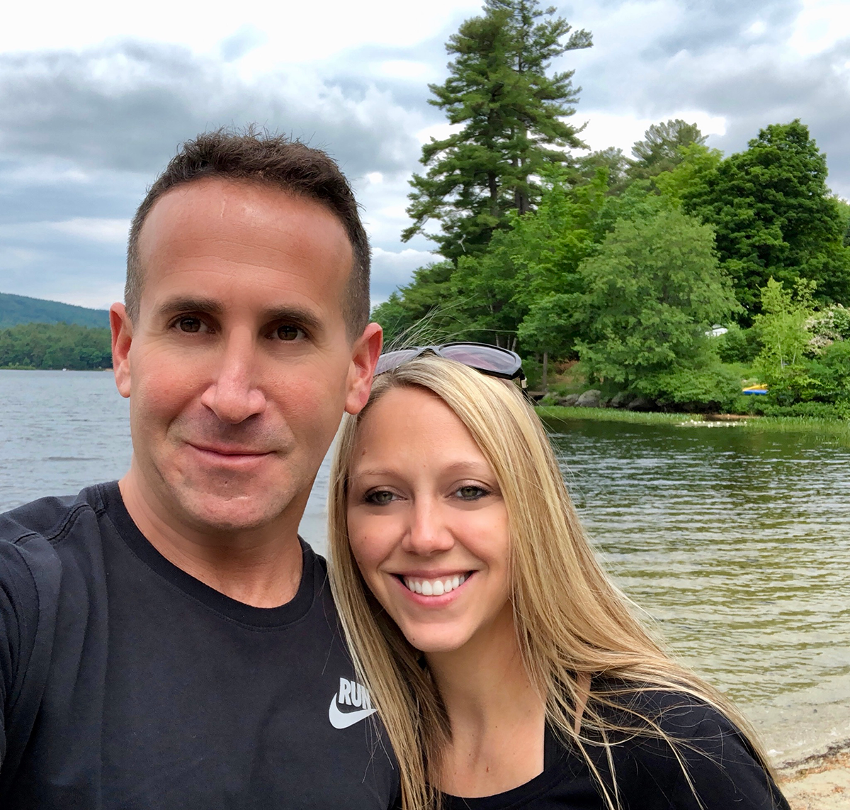 A couple smiles for the camera in front of beautiful scenery.