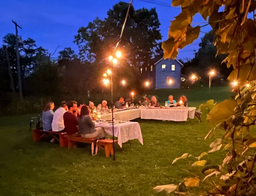 A view of one of Elman's outdoor dinners, in open grass under string lights.