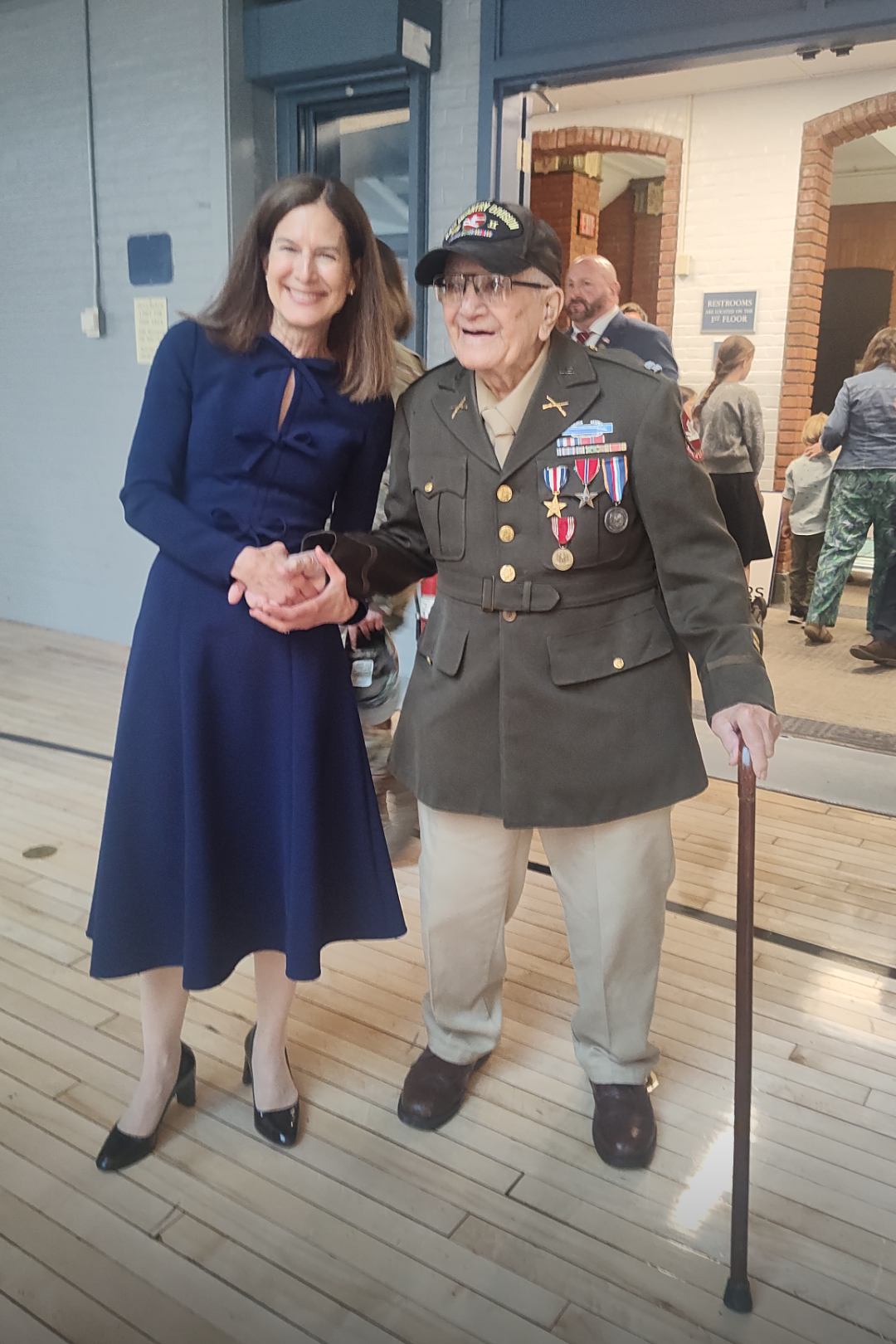 James V. Morgan in uniform and medals, walking with cane and smiling.