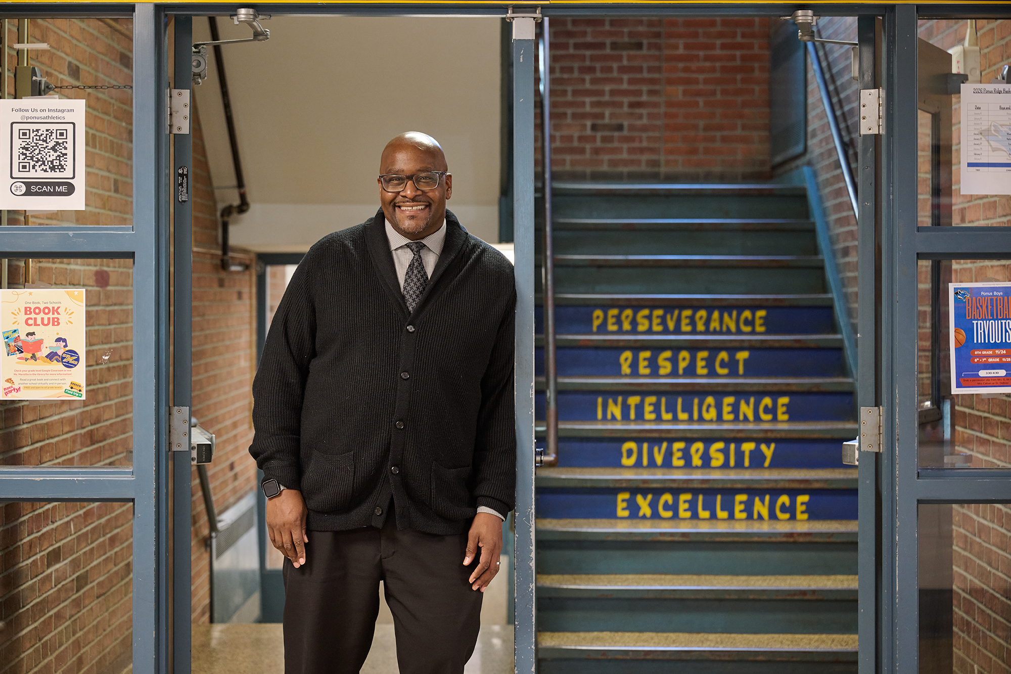 Lewis smiles pleasantly to the left of a staircase, where the words: perseverance, respect, intelligence,diversity, and integrity are painted on the steps.