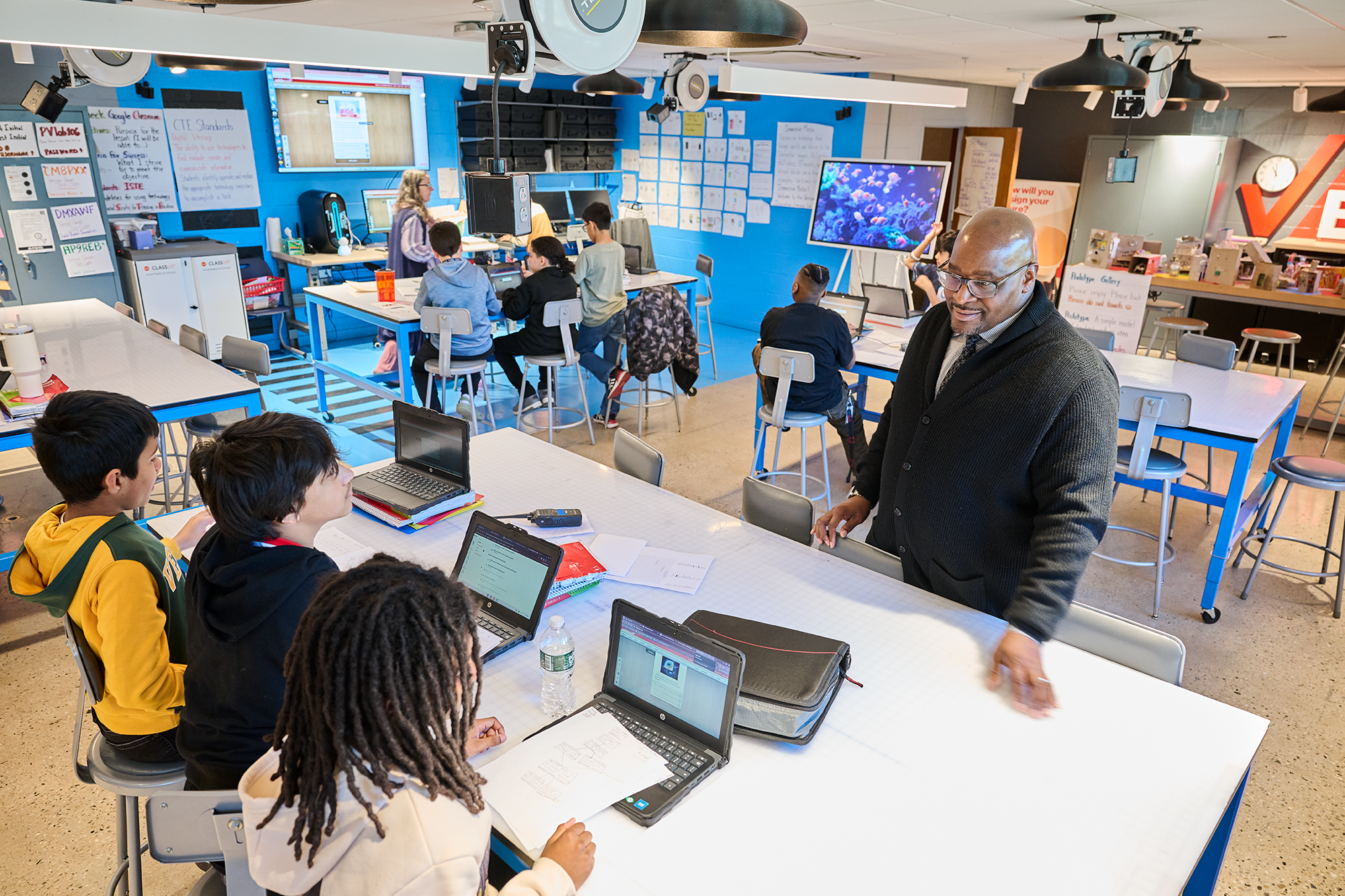 Lewis checks in on students in the Verizon Learning Lab, where students tackle real-world problem with the help of virtual reality, AI, and 3D printers.