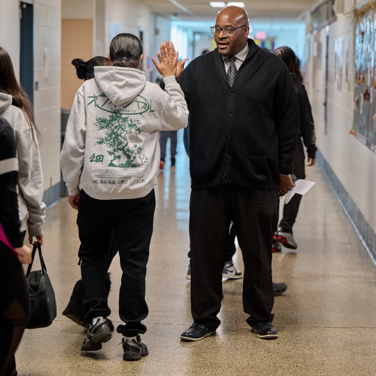 Lewis high-fives a student in the school's hallway.