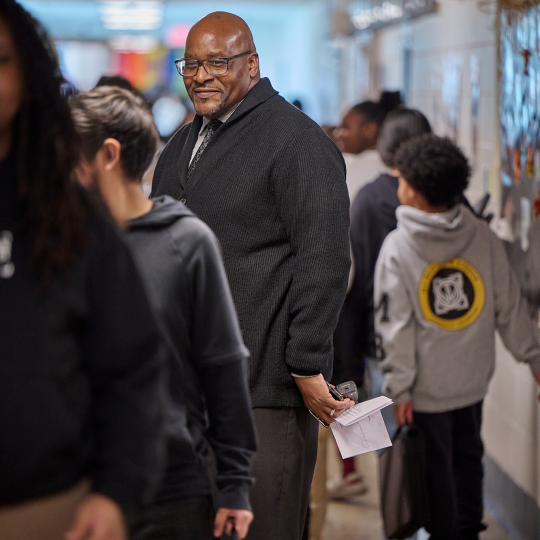 Lewis stands in the middle of a busy school hallway.