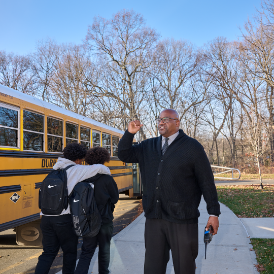 Lewis watches the children embark on the school bus home.