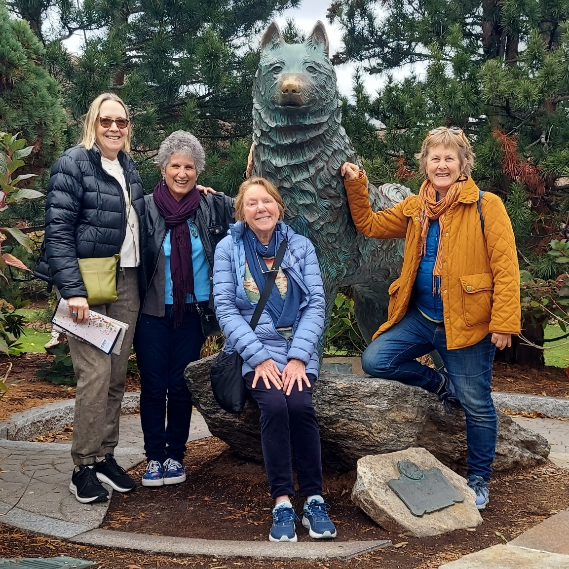 A group of UConn alumni friends smiling for the camera in front of husky statue.